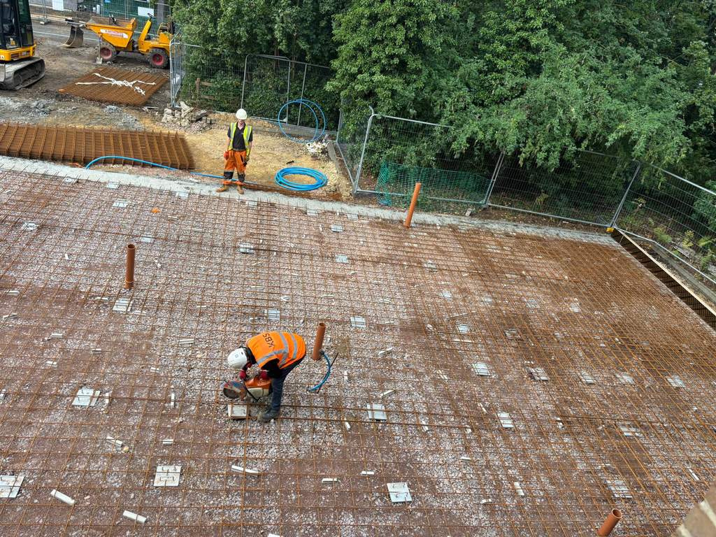 Crew fixing steel reinforcement mesh across new slab area