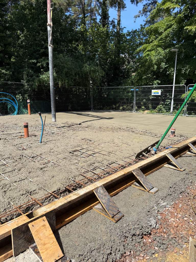 Freshly screeded concrete slab curing in summer sunshine