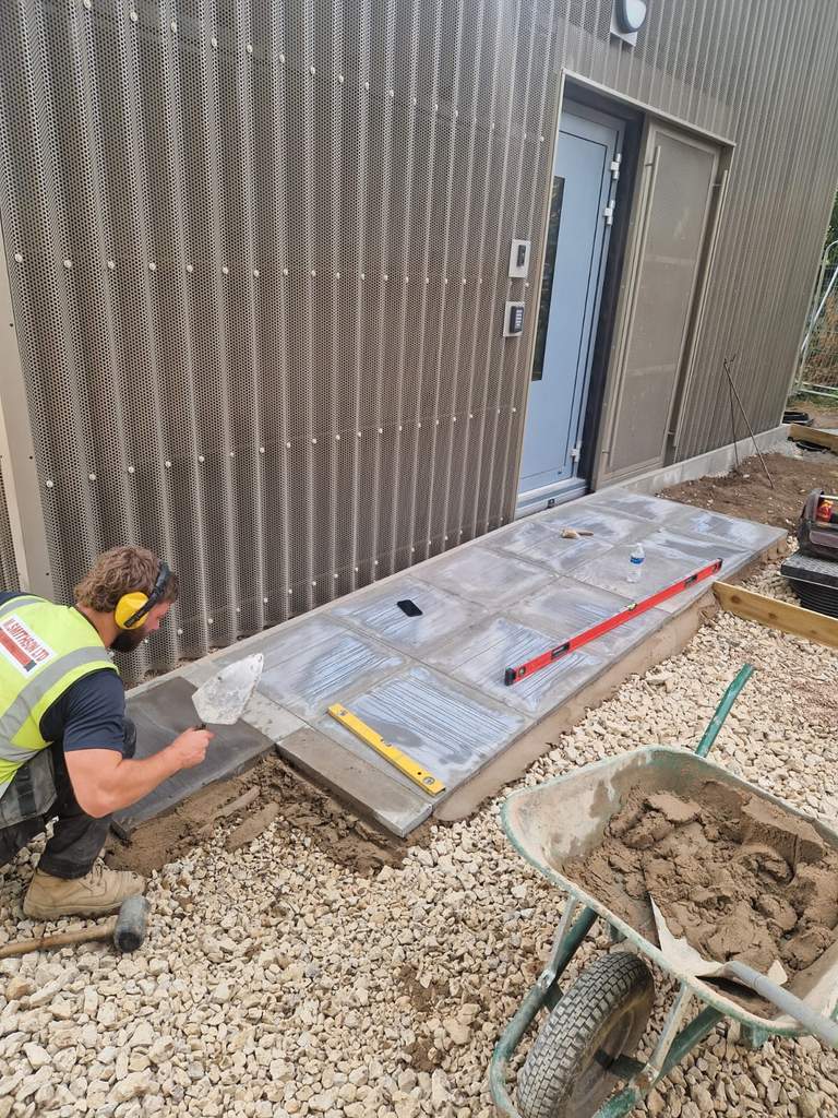 M.Smithson operative laying level paving slabs at new building Derby WMCA site