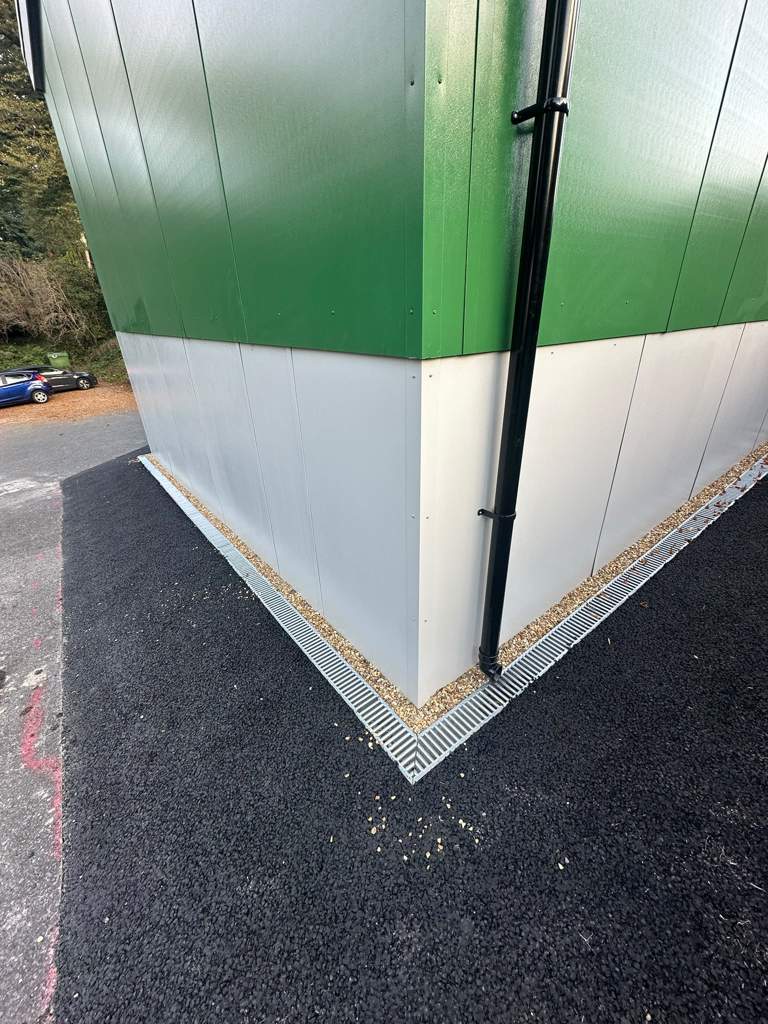 Fresh tarmac and wrap-around drainage at the building corner