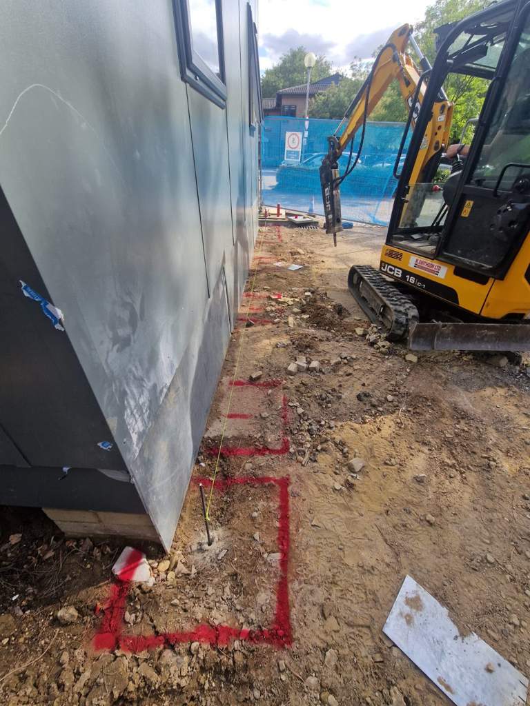 Mini excavator working to set-out lines along the elevation