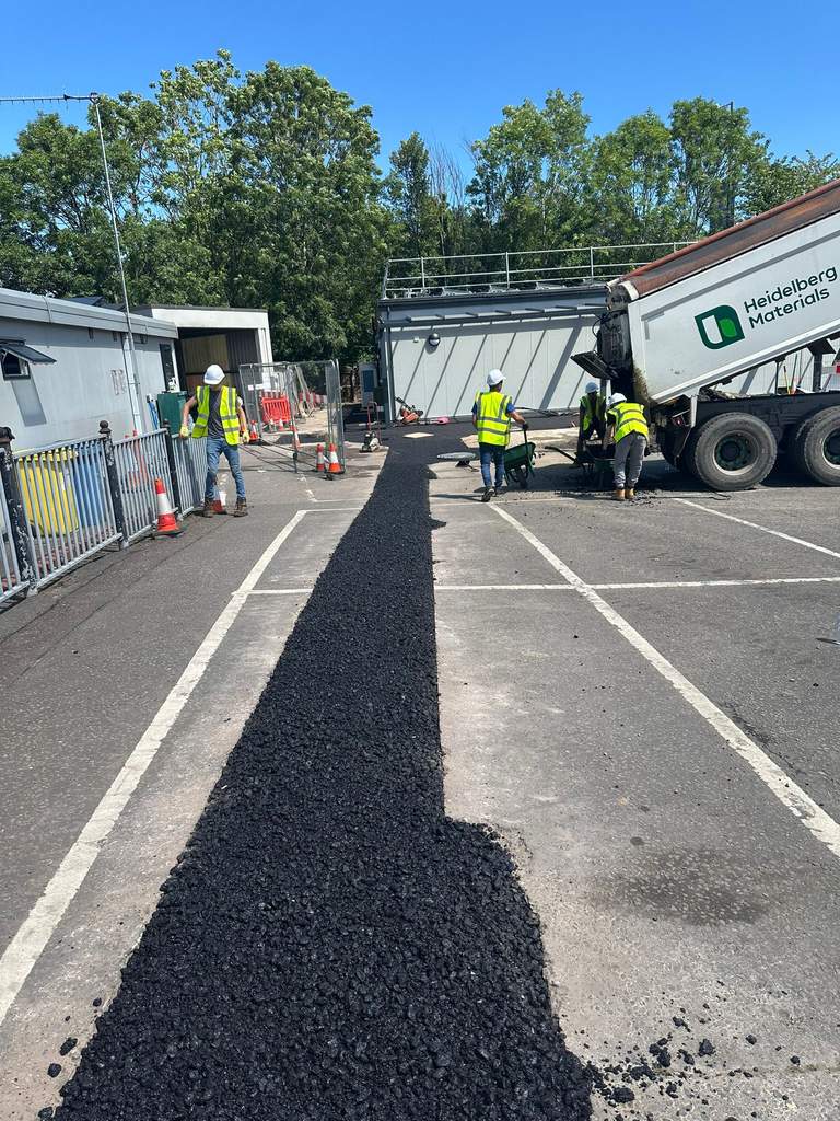 Crew laying fresh tarmac trench reinstatement from tipper lorry