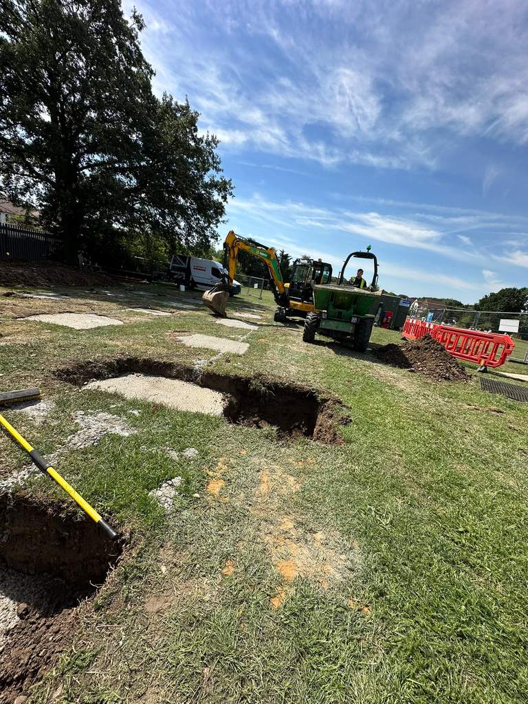 Excavator and dumper digging pad foundations under blue sky
