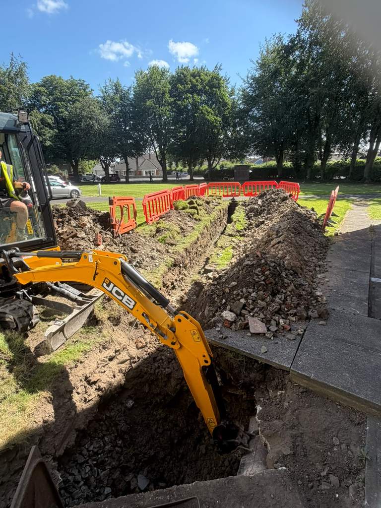 JCB excavator digging drainage trench at Hewlett Court care home Ramsbottom