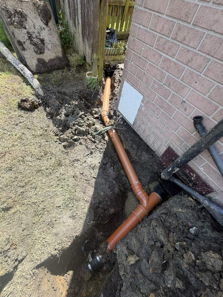 New underground drainage pipework installed alongside brick house