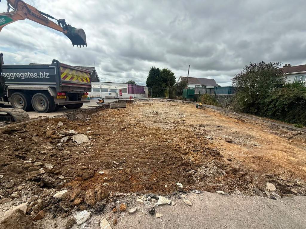 Cleared and levelled demolition site with grab lorry loading