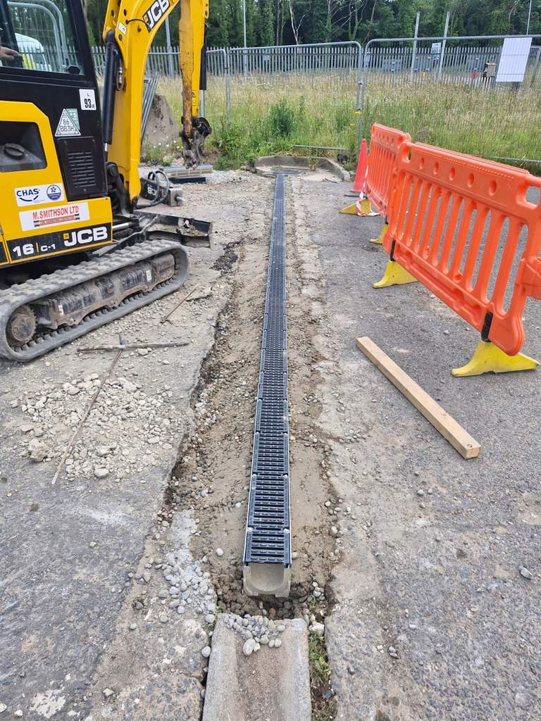 Branded JCB mini excavator beside newly installed linear drainage channel