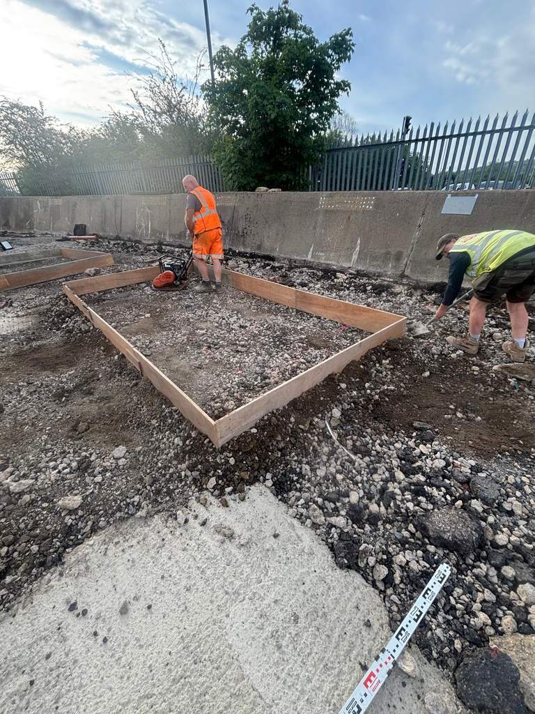 Groundworkers setting timber formwork and compacting foundation bases