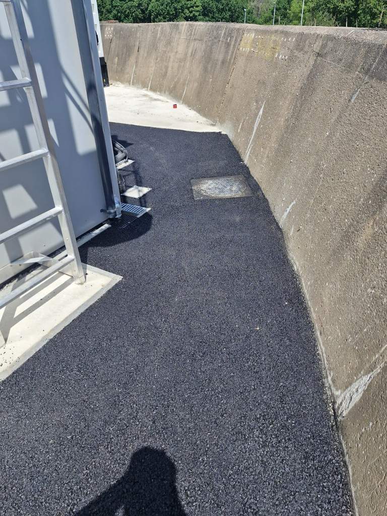 Completed tarmac pathway laid tight against curved retaining wall