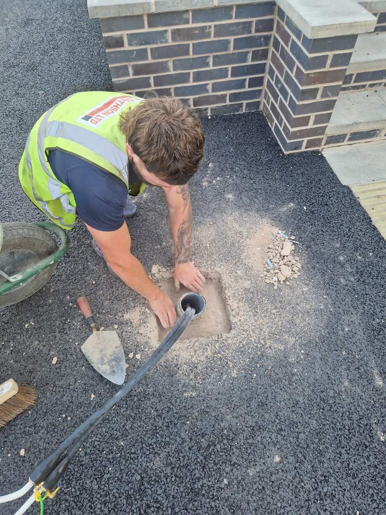 Groundworker finishing ducting chamber beside new blue engineering brickwork