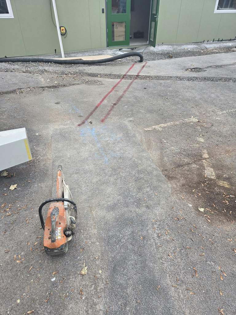 Saw-cutting and marking out a service trench across the tarmac