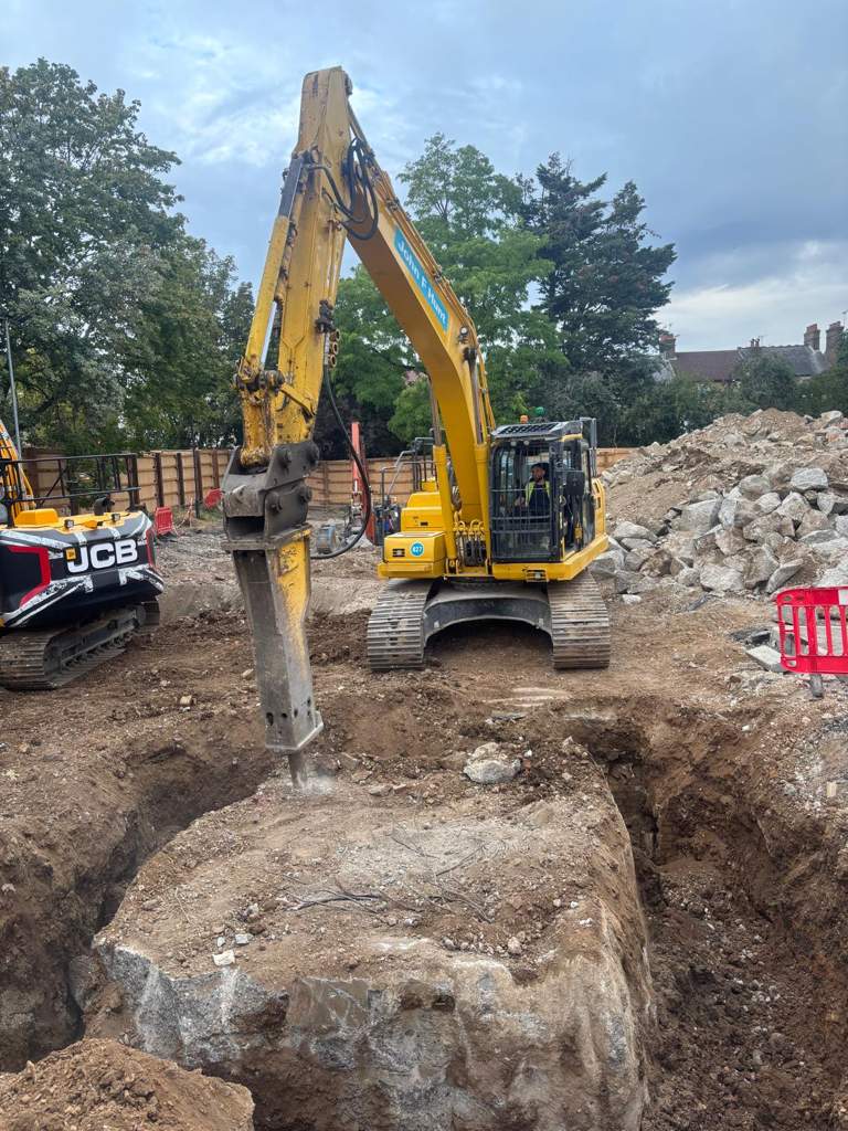 Hydraulic breaker splitting a massive buried foundation block