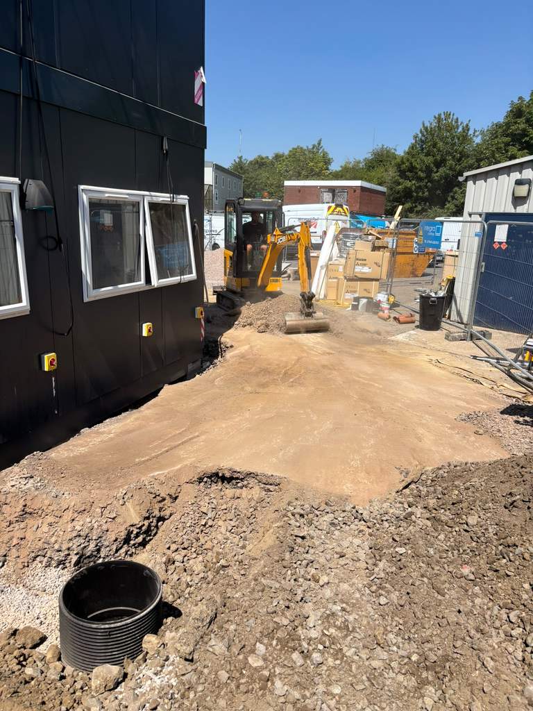 JCB mini excavator grading ground beside new building at Westbury Wiltshire — M.Smithson LTD