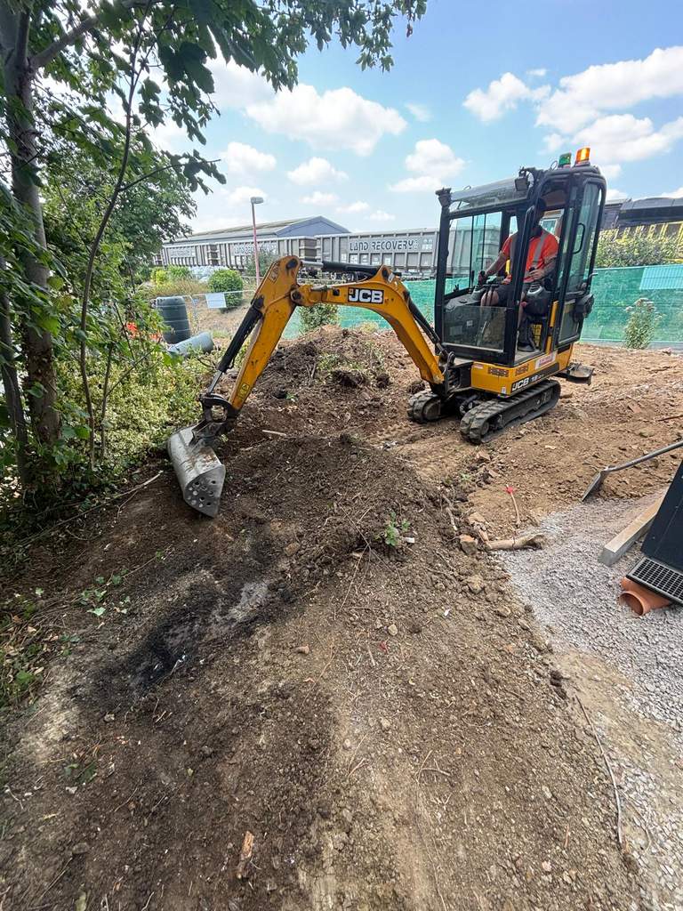 JCB 19C excavator excavating landscaped area at Westbury