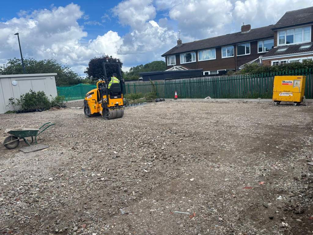 JCB roller compacting hardcore sub-base across the car park