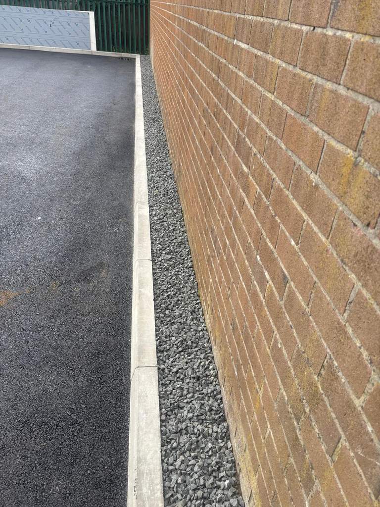 Crisp tarmac edge detail with kerb and gravel drainage strip